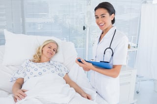 Smiling doctor standing next to her patient in hospital room.jpeg