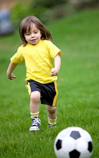 happy kid playing football in a park outdoors. bow legs diagnoses.jpeg